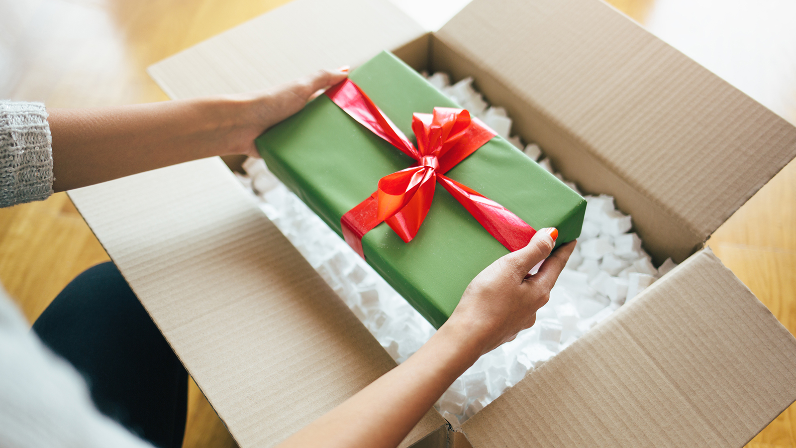 Person Opening Gift From Shipping Box person pulling gift from box